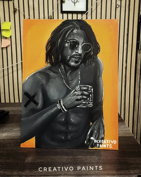 My acrylic painting of Shah Rukh Khan, displayed on a desk. This piece combines a monochrome portrait with a striking yellow-orange background.