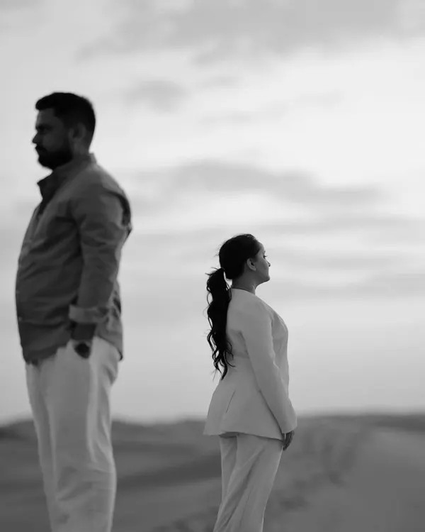 A powerful and artistic black and white portrait in the desert. The composition and their expressions create a moody, cinematic, and deeply contemplative image.