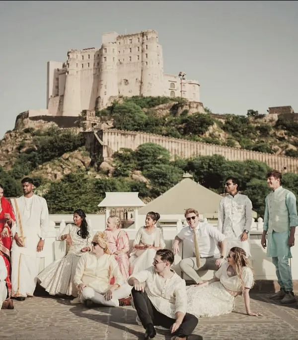 A grand group portrait of the wedding party at Alila Fort Bishangarh. The historic fort provides an epic, larger-than-life backdrop for these unforgettable moments.