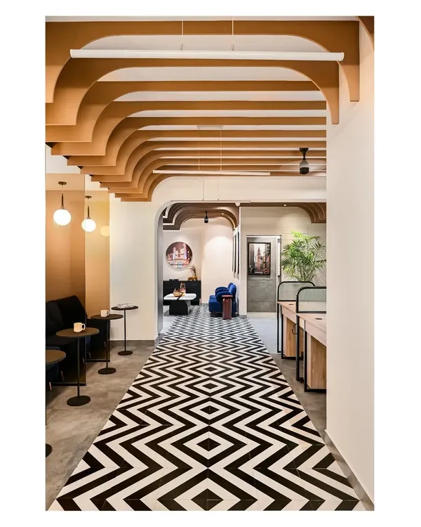 The central corridor of the Centennial College office features a bold black-and-white tiled floor and arched ceiling fins, creating a strong visual path that connects the various zones.