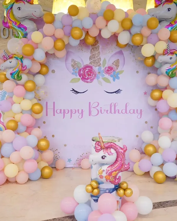 A bright and cheerful unicorn-themed birthday decoration. This setup features a pastel balloon arch, a large unicorn backdrop, and multiple unicorn foil balloons, perfect for a magical celebration.