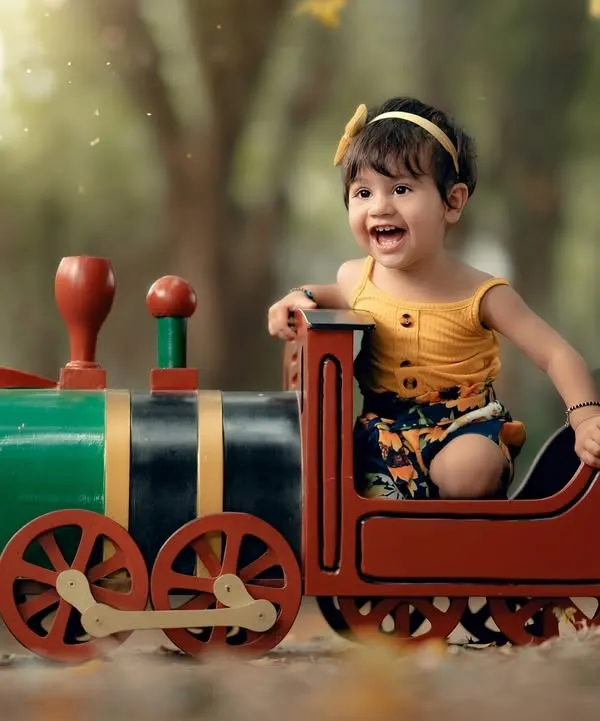 This is what pure joy looks like. I love creating these playful outdoor scenes, like this one with a little girl on a toy train, where kids can just be themselves and their happiness shines through.