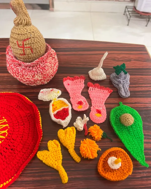 All the individual, hand-crocheted elements of my pooja thali set laid out, including a kalash, betel leaf, flowers, and other traditional items.