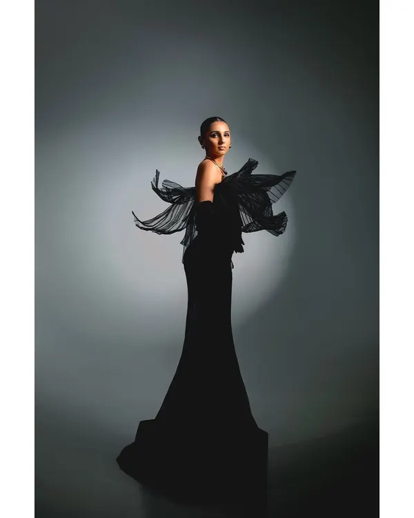 A full-length shot of Masoom Minawala for the Elle Digital cover story. The focus is on the garment's dramatic silhouette, using a single spotlight to sculpt the form and create a sense of classic Hollywood glamour.