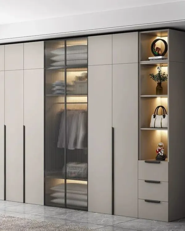 A floor-to-ceiling wardrobe combining closed cabinets with a central fluted glass section. The internal lighting beautifully showcases the contents while maintaining privacy.