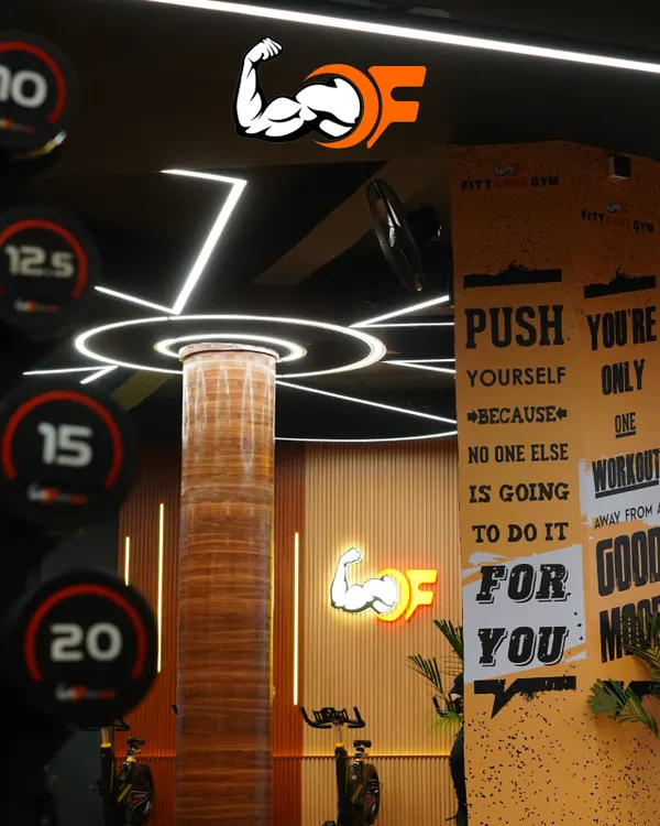 An inside look at our gym's motivating atmosphere, featuring our iconic logo, modern lighting, and inspirational wall art that reminds you to push yourself.