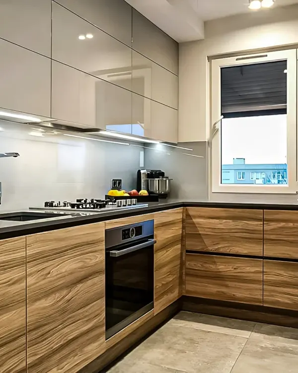 A sleek L-shaped kitchen combining high-gloss grey upper cabinets with warm wood-grain lower cabinets. We installed under-cabinet LED lighting to illuminate the black granite countertop and ensure a well-lit workspace.
