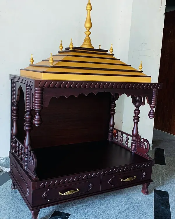 A full view of a traditional, handmade wooden mandir. This unique piece features intricately turned pillars, carved details, and a tiered roof with golden accents, creating a truly special place for prayer.