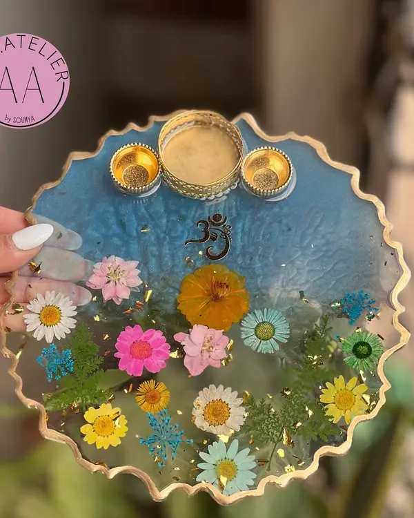 A beautiful blue resin pooja thali, handcrafted with real flowers, an Om symbol, and brass bowls for your daily rituals.