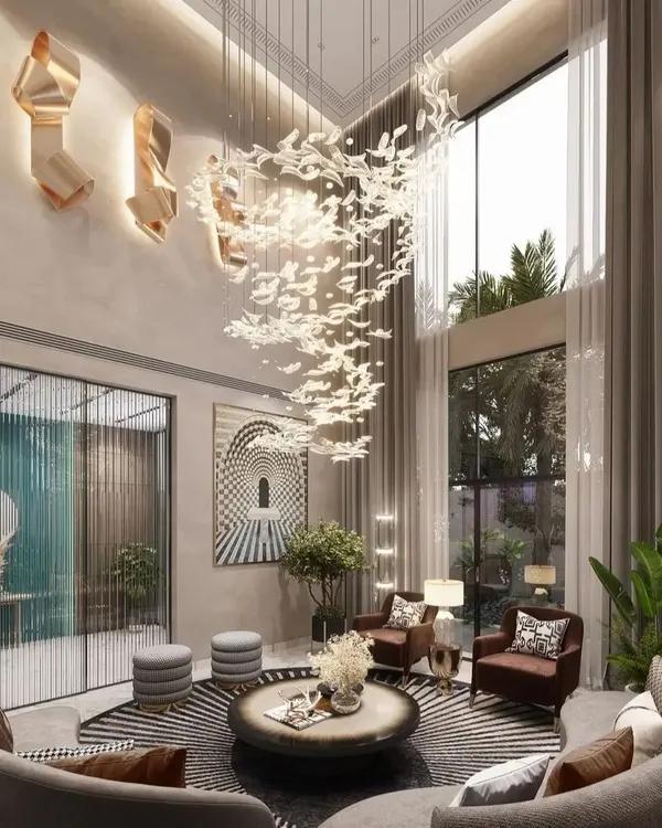 A double-height living room in a Rohtak residence, where a magnificent cascading chandelier and soaring windows create a sense of grandeur and connection to the outdoors. The curved seating arrangement encourages conversation and togetherness.