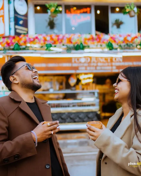 A candid shot of a couple sharing a laugh over a cup of chai on Mussoorie's Mall Road, capturing a genuine and joyful moment.
