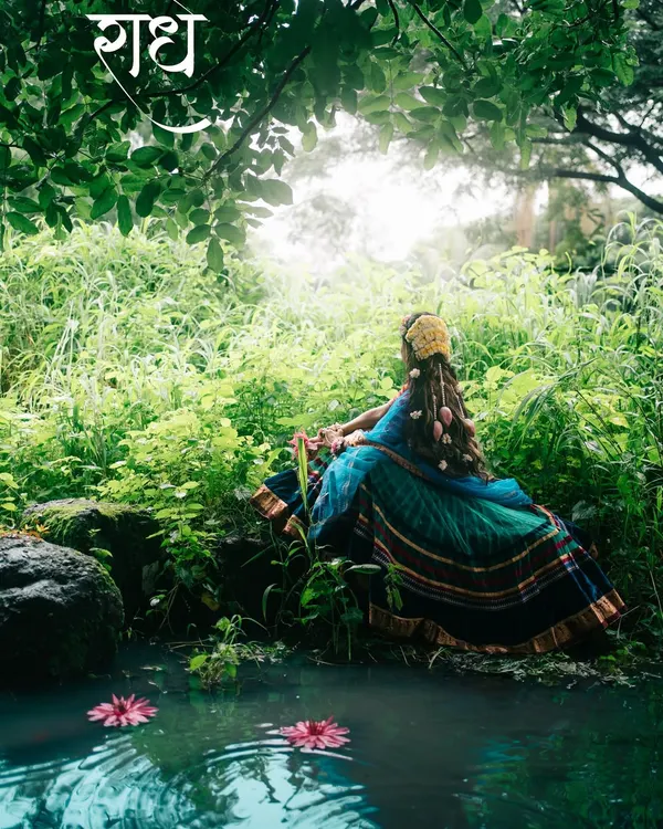 A conceptual portrait capturing the serene and divine essence of Radha, lost in thought by the water in a lush, green forest.