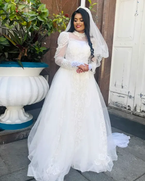 A full-length view of our beautiful bride in her rental wedding gown. This design features delicate lace, elegant long sleeves, and a flowing tulle skirt for a timeless and romantic look.