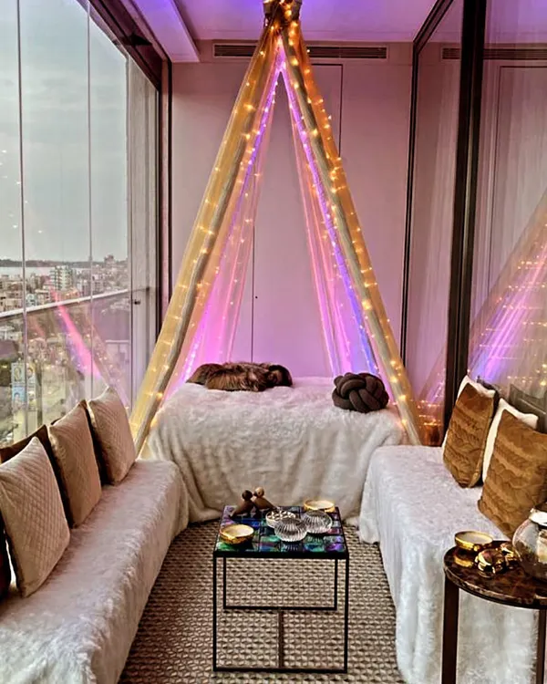 A cozy seating arrangement we created on a balcony with a beautiful city view. The setup includes a teepee-style canopy bed and comfortable floor seating, perfect for a relaxed evening.