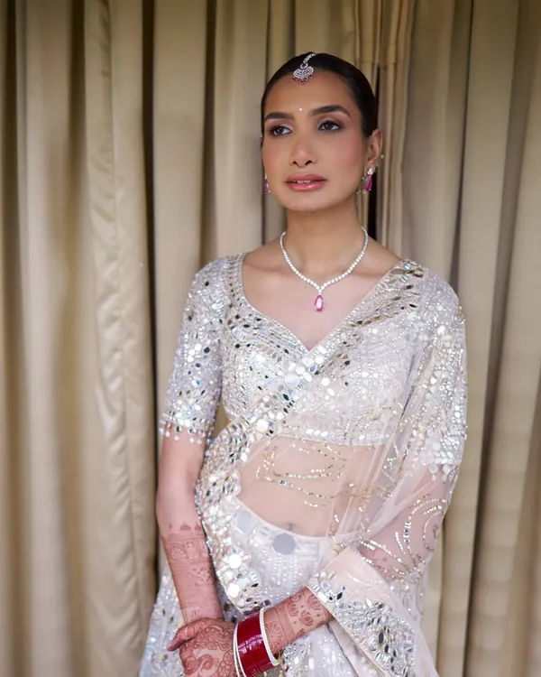 For a Goa wedding, you have to be ready for sun and humidity. We matched her ivory mirror-work lehenga with a luminous, long-lasting base, soft champagne lids, and a sleek bun with baby's breath.