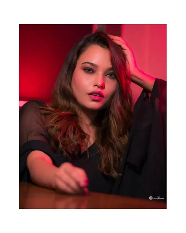 A close-up portrait using red gel lighting to create a bold, cinematic feel. The focus is on the intense expression and the play of light and shadow.