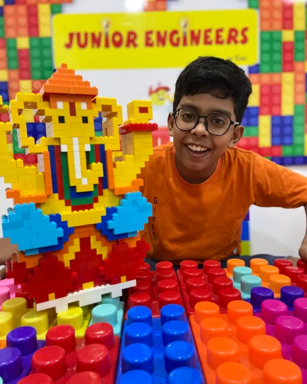 A student beams with pride next to his large, colorful LEGO Ganesha. Our themed workshops blend cultural celebration with hands-on STEM learning.