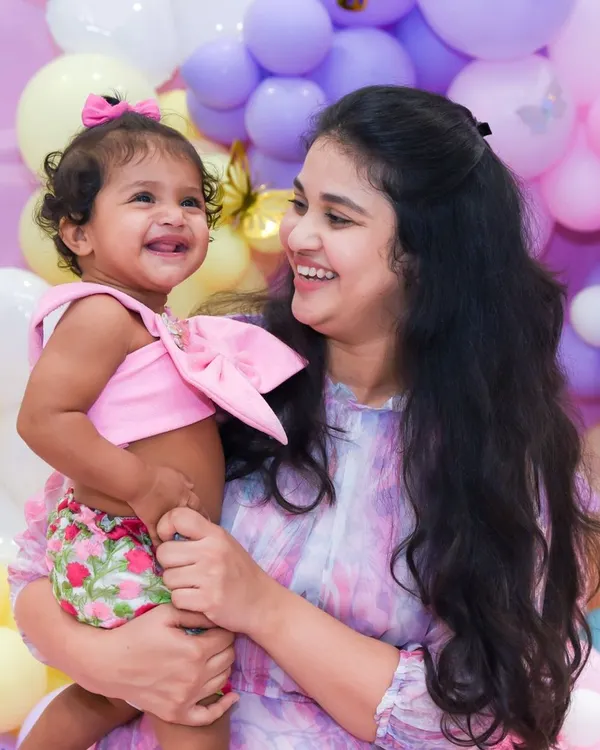 A candid moment of pure joy shared between a mother and her laughing baby girl against a backdrop of pastel balloons. We believe these unscripted moments are the most precious memories from any family event.