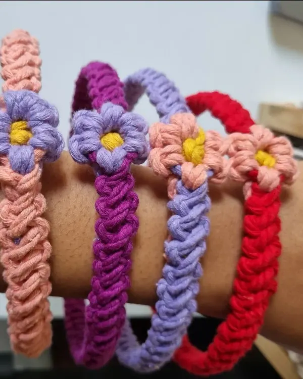 A collection of my floral macrame headbands worn on the arm to show their flexibility and vibrant colors. Each one is hand-knotted with a delicate flower accent, perfect for festivals or everyday style.