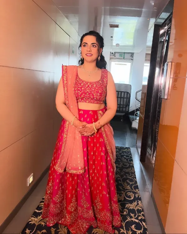 A beautiful bridesmaid in a vibrant pink lehenga. The makeup is fresh and pretty, with a focus on glowing skin and soft pink tones.