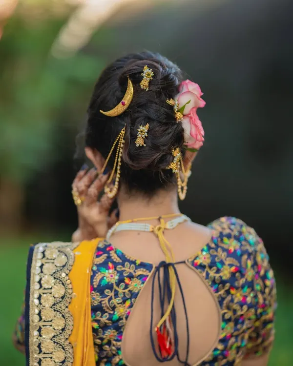 A detailed view of a modern messy khopa, adorned with a delicate chandrakor pin and fresh flowers. This style combines tradition with a contemporary, softer feel.