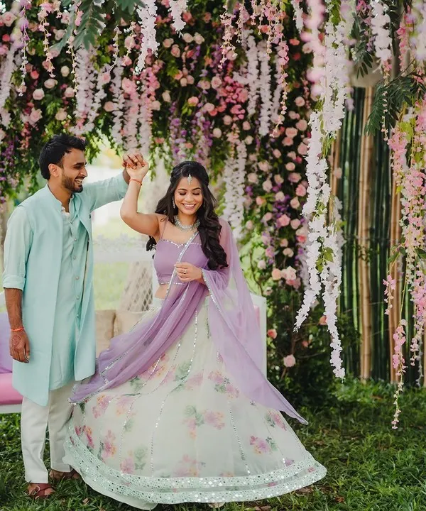 A couple dancing under a breathtaking canopy of hanging wisteria, creating a fairytale moment for their garden-themed celebration.