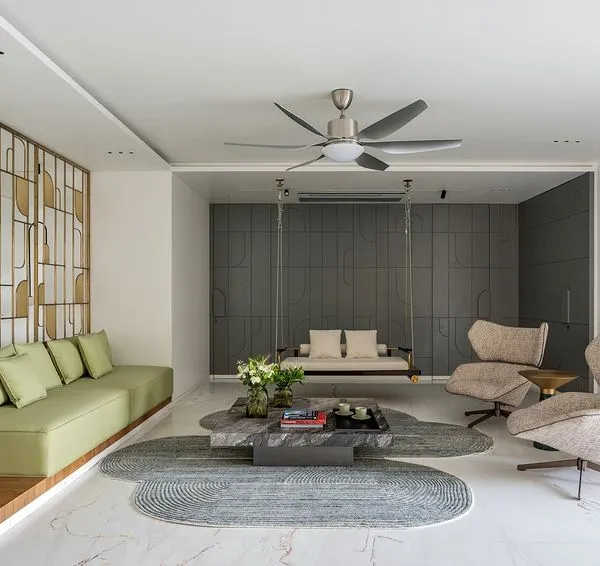 This formal living space from my Park West project embodies my design philosophy of creating tranquil, sophisticated environments. I used a layered neutral palette, punctuated by the soft green of the sofa and the warmth of a custom brass partition, to create distinct zones that flow into one another. The indoor swing adds a touch of playful serenity, making the space feel both grand and intimately personal.