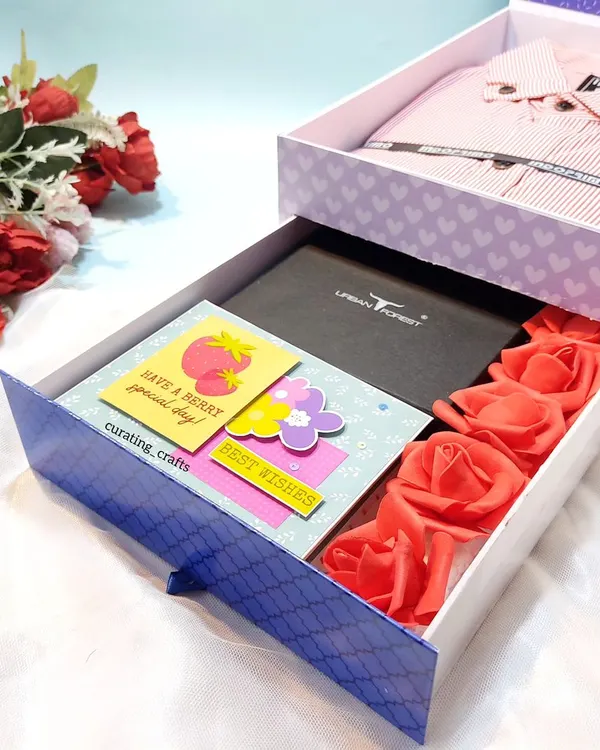 This is my signature 'Shirt Box' hamper, which features a pull-out drawer. The drawer holds a wallet, a mini scrapbook, and some decorative roses, while the top compartment holds a folded shirt.