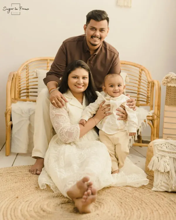 A relaxed and happy family portrait in our signature boho style. The family sits together on a jute rug in front of a rattan bench, creating a warm and inviting scene.