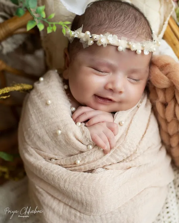 A sweet newborn smile is the most precious thing to capture. This little one is dreaming happy dreams, all wrapped up and cozy.