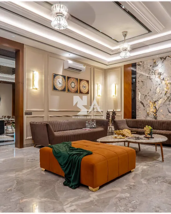 In this drawing room, we used an exotic stone slab as a dramatic backdrop, highlighted by ambient lighting. The rich textures of the stone, paired with plush brown sofas and a vibrant orange ottoman, create a space that is both opulent and welcoming.