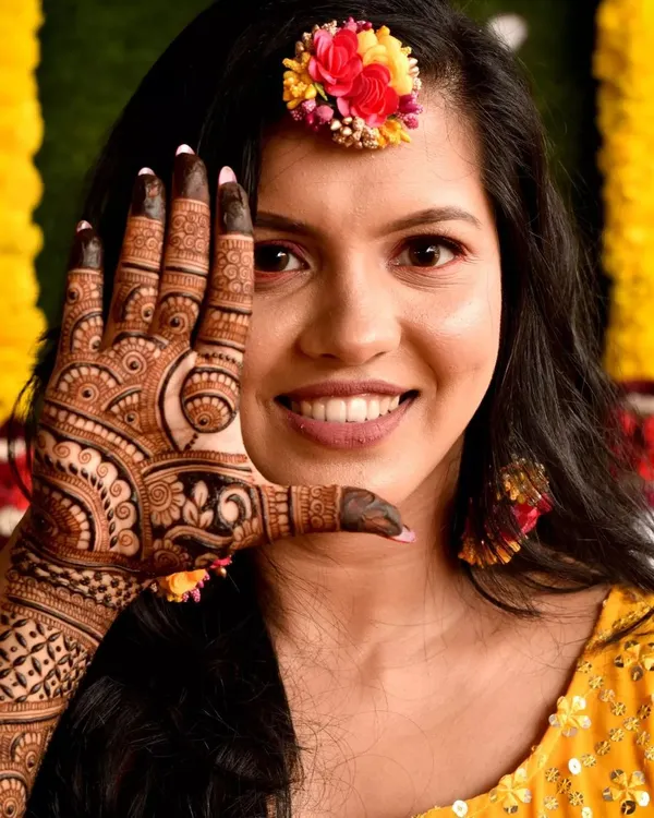 A happy bride makes my day! Here she is, framing her beautiful smile with her bridal mehendi. The design features dense patterns on the fingers and a detailed palm, perfect for those classic wedding photos.