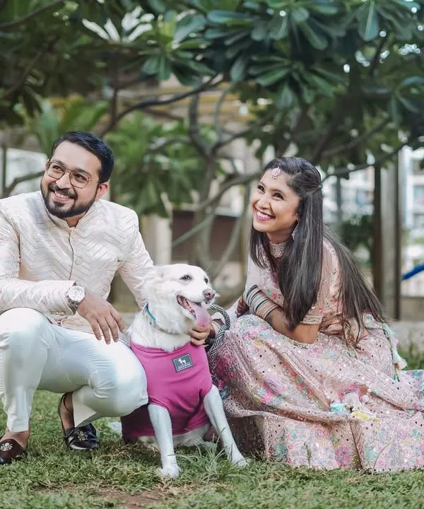 A happy couple in elegant ethnic wear posing with their adorable dog in a green park. I love when couples bring their pets along, as it adds a personal and joyful touch to the pre-wedding photos.