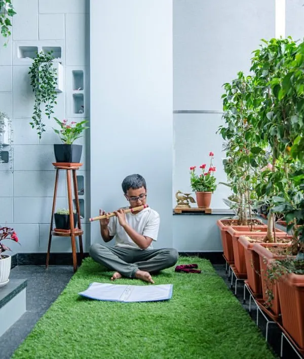 Close to divinity. We create spaces that encourage mindfulness and peace. This serene corner, with its lush green carpet and rows of potted plants, is a perfect spot for meditation or playing music.