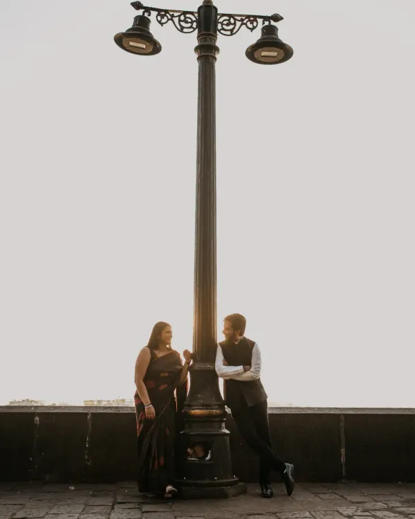 A classic, romantic portrait under a vintage lamppost in Mumbai. This shot captures the timeless charm of the city, creating a quiet, intimate moment against the evening sky.
