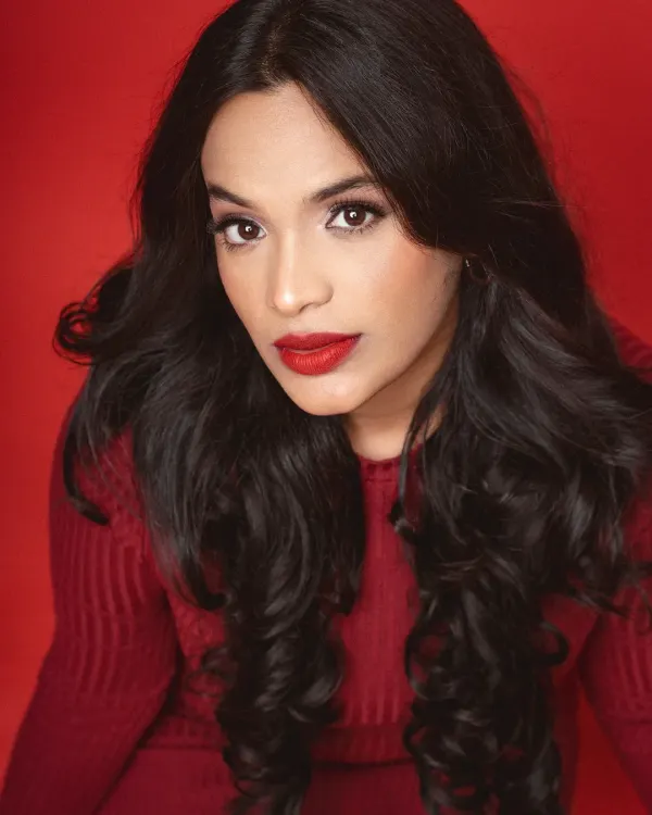 A powerful close-up portrait against a vibrant red studio backdrop. The model's direct gaze and the rich color saturation create a bold and confident statement.