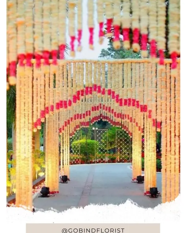 This is a beautiful entrance tunnel I created entirely from fresh flower strings. The mix of white and pink flowers forms an archway that guides guests into the venue with warm lighting.