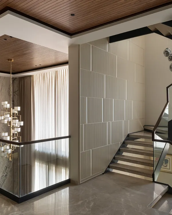 This sculptural staircase connects four floors, acting as the central spine of the home. Its floating design, framed by fluted wall panels and a modern chandelier, creates a sense of lightness and vertical grandeur.