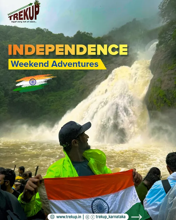 Celebrating freedom with an adventure. A trekker with the Indian flag at a powerful waterfall during our Independence Weekend trip.