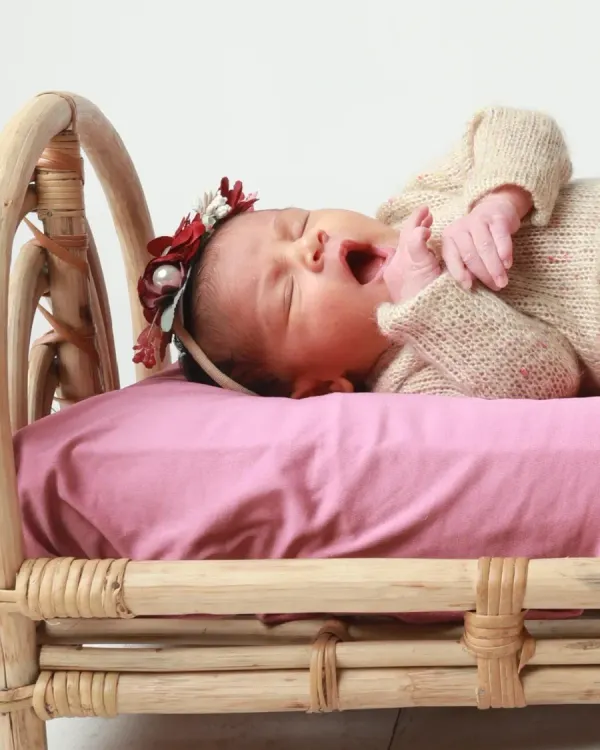 A sleepy yawn from a 21-day-old newborn. Even as they get a little older, we can still capture these incredibly precious and delicate moments. This little one is resting comfortably on a miniature rattan bed, a popular prop for my newborn sessions.