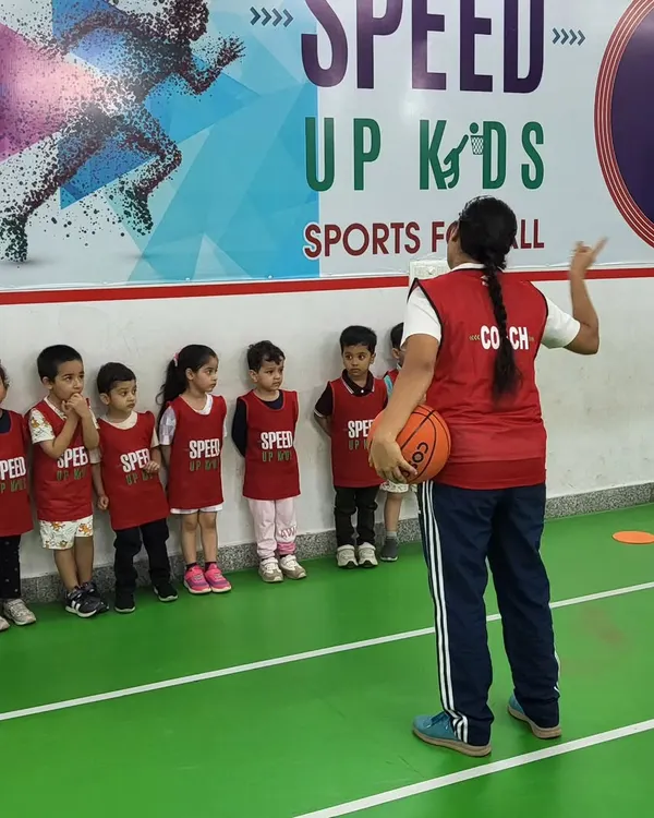 A coach addresses a line of young athletes, explaining the next drill. Clear communication and a structured approach are key to our teaching method.