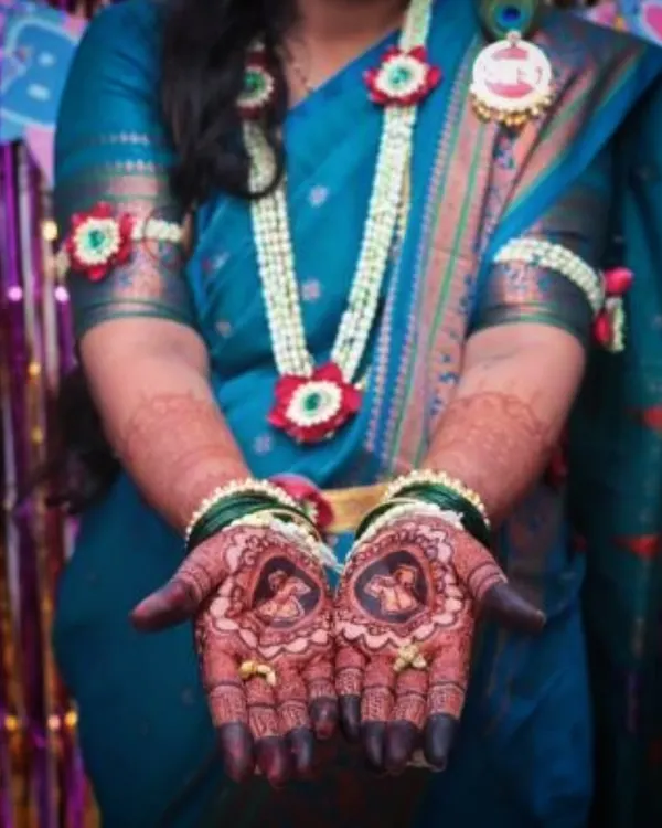 A beautiful shot of a mom-to-be showcasing her baby shower mehendi. The design includes portraits of a couple, celebrating their journey to parenthood.
