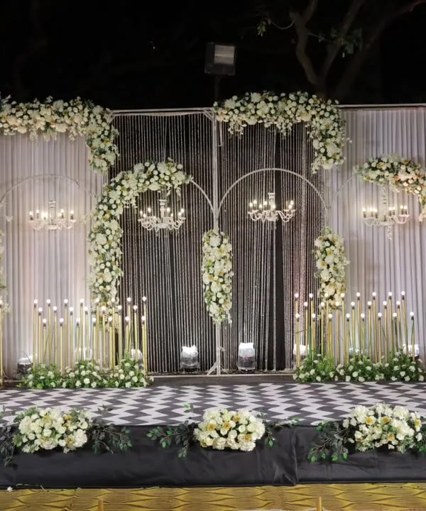 I believe a reception stage shouldn't just be a backdrop, but the heart of the celebration. For Roshan and Ria, I designed this elegant masterpiece with cascading white florals, classic chandeliers, and a distinct checkered floor to create a setting that was both grand and timeless.
