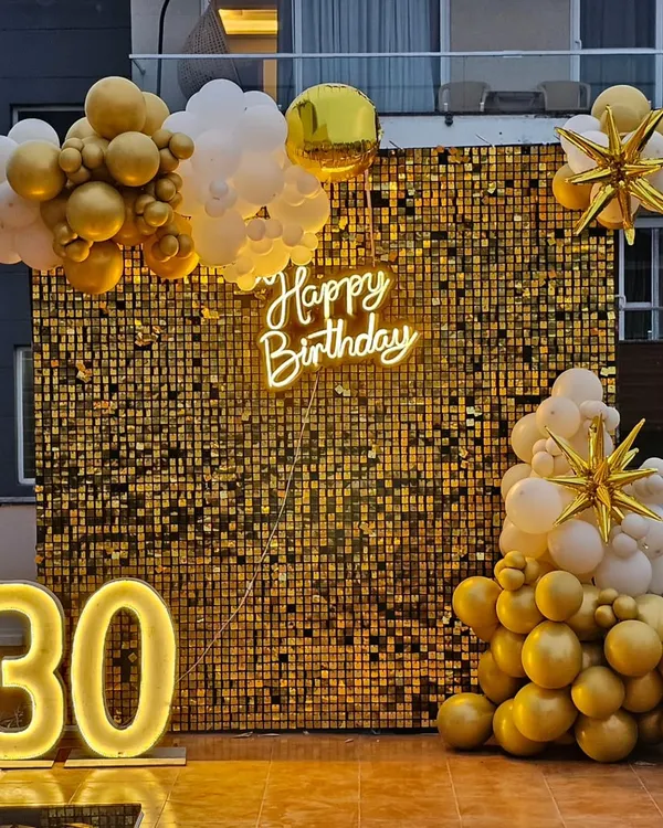 A glamorous 30th birthday setup featuring a full gold sequin shimmer wall, a custom 'Happy Birthday' neon sign, and large light-up marquee numbers. This is one of our most popular backdrops for photos.