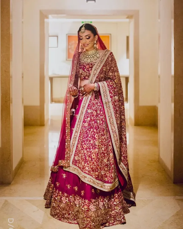 A full-length view of a breathtaking bride in her deep red lehenga. I crafted a classic bridal look with defined eyes and glowing skin to ensure she looked and felt like royalty.