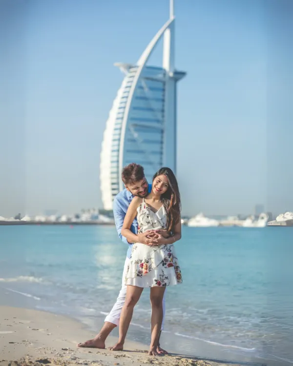 An iconic Dubai pre-wedding portrait. The couple shares a happy moment on the beach, with the magnificent Burj Al Arab standing tall in the background.