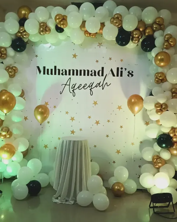 An elegant black, white, and gold balloon arch for Muhammad Ali's Aqeeqah ceremony. The starry backdrop and simple color scheme create a refined and celebratory setting for this important religious event.