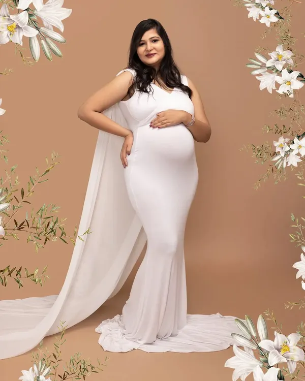 The definition of elegance. This mother-to-be is wearing a beautiful white cape gown from my studio collection, creating a classic and graceful silhouette against a simple backdrop.