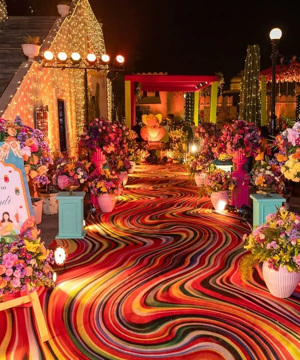 A truly vibrant Mehendi entrance, where a psychedelic-print carpet runner and overflowing floral arrangements create an explosion of color. I designed this to be an immersive and high-energy welcome for guests.