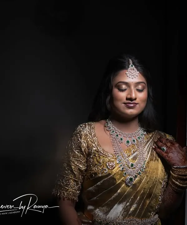 Pooja looking serene and glamorous for her reception. The dramatic lighting highlights the flawless, glowing finish of her makeup, paired with a stunning gold and white saree.